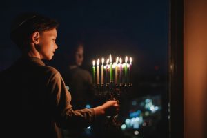 The,Child,Lights,The,Menorah,For,Hanukkah,On,The,Windowsill.